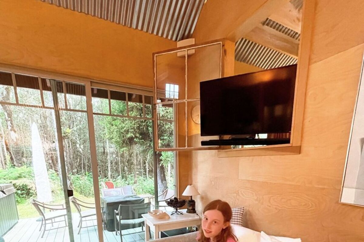 A%20girl%20enjoying%20a%20Hawaiian%20bungalow%20sitting%20on%20a%20bed%20with%20rainforest%20outside%2E