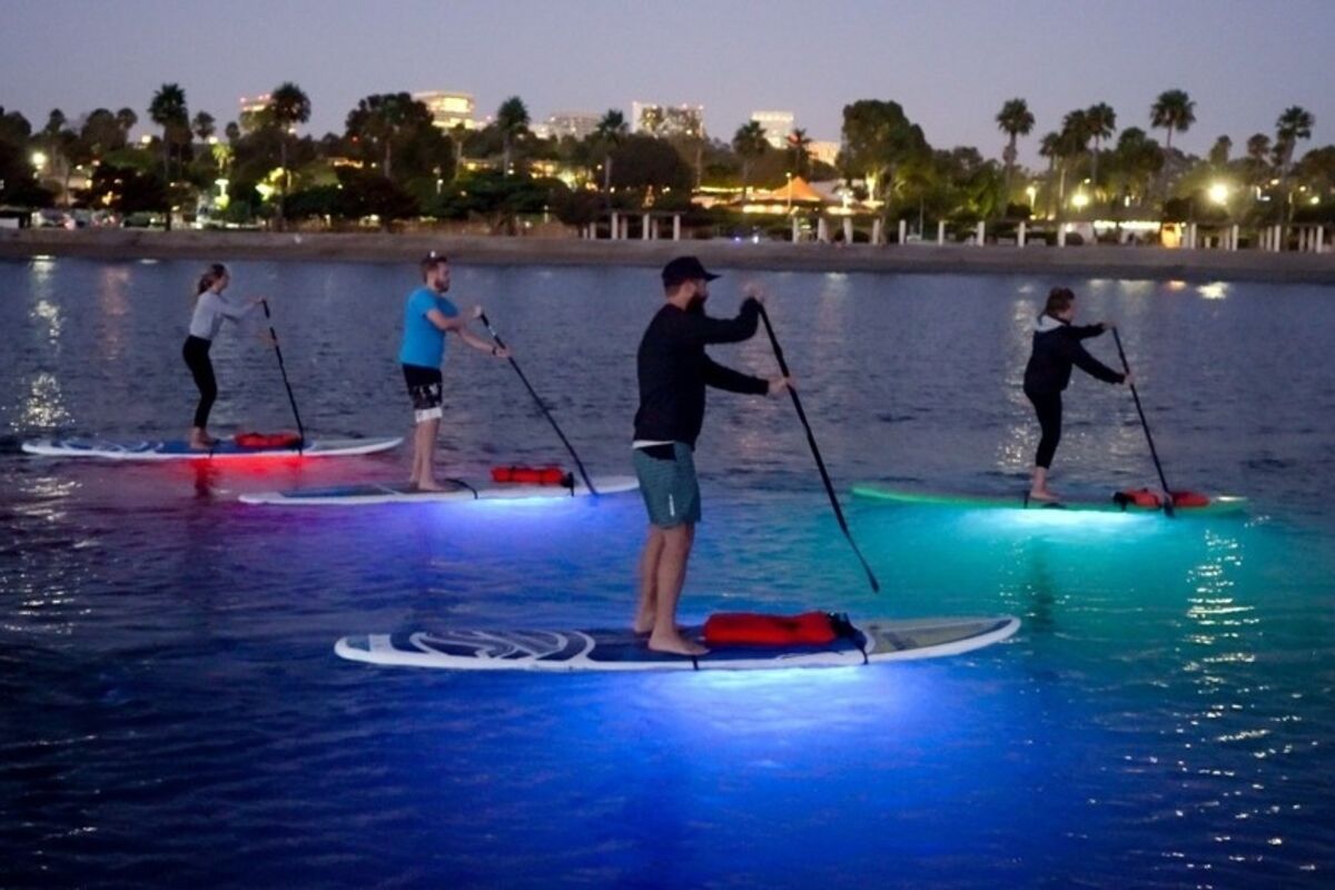 Three%20people%20doing%20nighttime%20stand%20up%20paddleboards%20in%20a%20lagoon