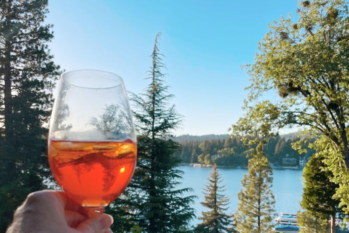 Holding%20an%20aperol%20spritz%20on%20balcony%20overlooking%20Lake%20Arrowhead%2E