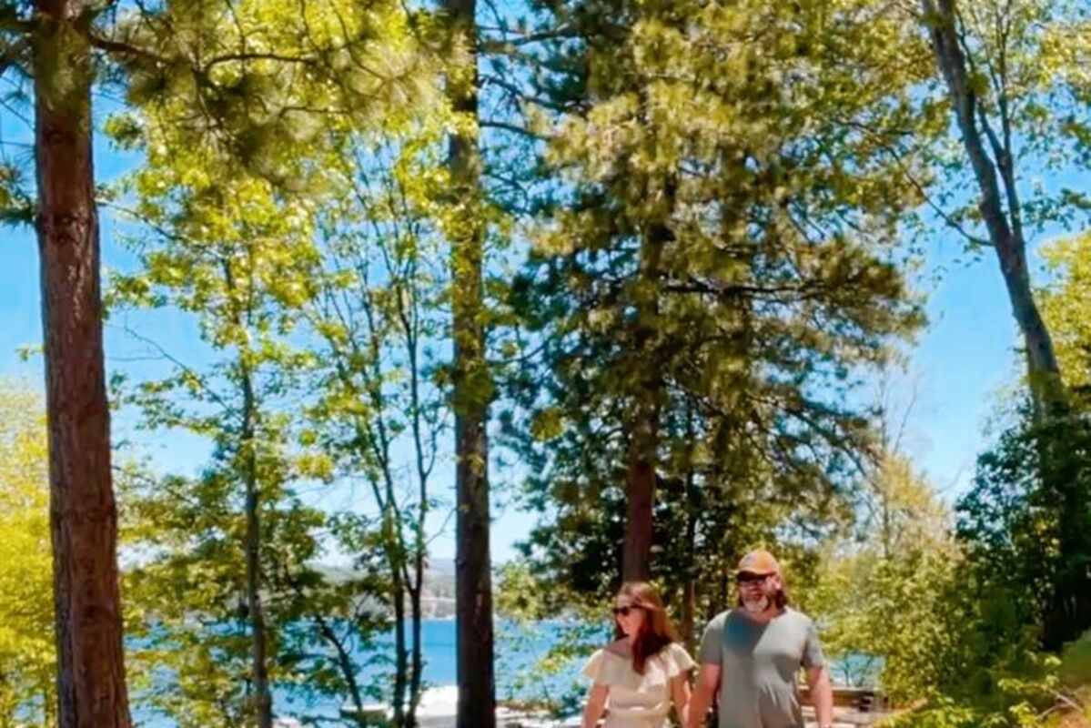 Couple%20walking%20with%20dog%2E%20Trees%20and%20lake%20in%20background%2E
