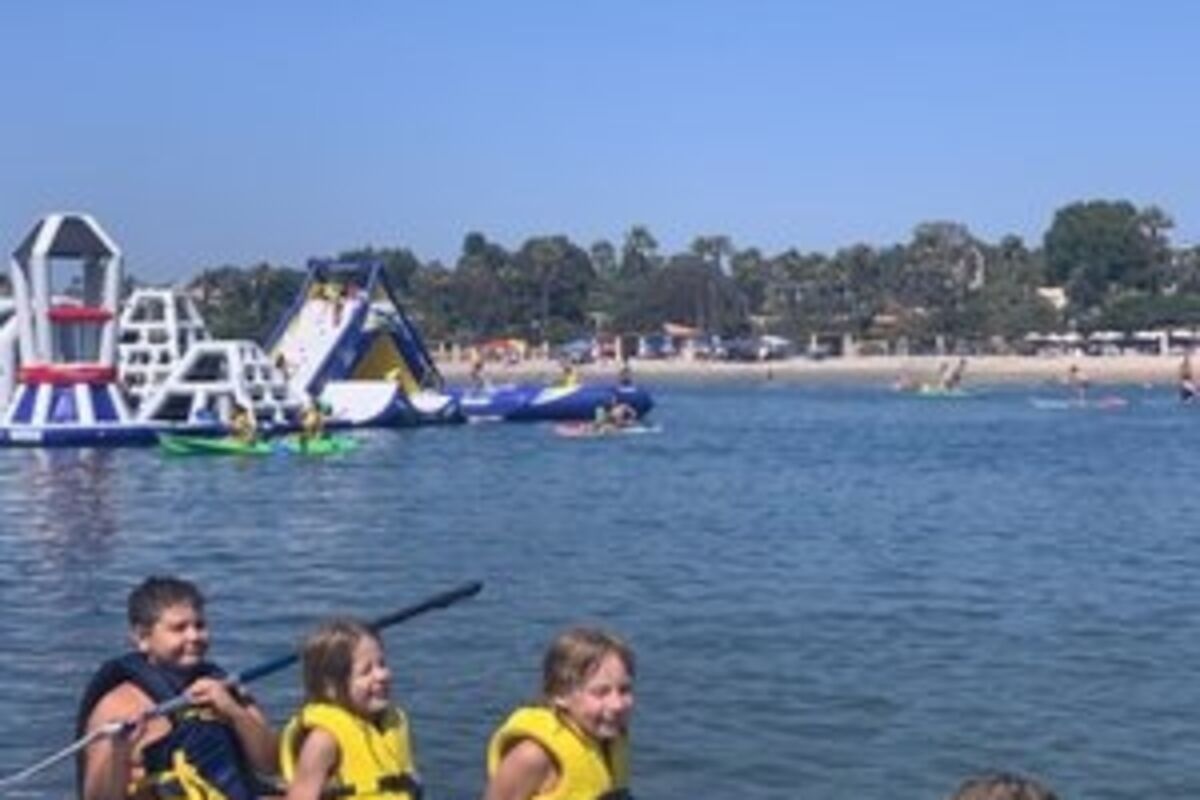 Four%20kids%20sitting%20on%20a%20stand%20up%20paddleboard%20with%20lifevests%2E
